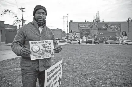  ?? ALBERT CESARE/CINCINNATI ENQUIRER ?? Stefan Pryor holds up a sign while standing next to a sign that he put out in Over-the-rhine’s Grant Park that reads, “Teach your son not to kill my son. I already taught my son not to kill yours.” Pryor has been placing the signs all over town.