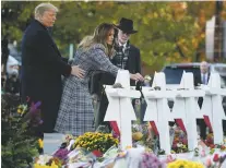  ?? ANDREW HARNIK/ASSOCIATED PRESS ?? First lady Melania Trump, accompanie­d by President Donald Trump, and Tree of Life Rabbi Jeffrey Myers, right, puts down a white flower at a memorial Tuesday for those killed at the Tree of Life Synagogue in Pittsburgh.