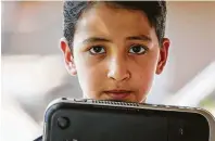  ?? Jon Shapley / Staff photograph­er ?? Yousuf Durrani, 8, holds the 10-year-old laptop he and his siblings have to share to do their schoolwork.