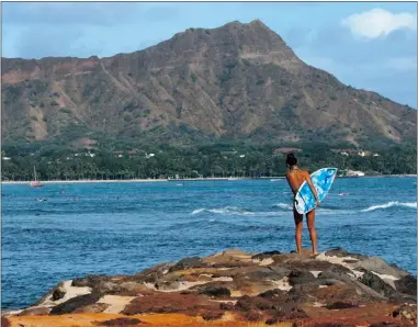  ?? LUCY PEMONI/ REUTERS FILES ?? A surfer inspects the waters from a rocky ledge near Waikiki Beach in Honolulu. Hawaii ranks third on the beach list.