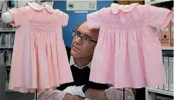  ??  ?? South Canterbury Museum social history curator Chris Rapley with two dresses lent to the museum, worn at the first birthday of many of the maker’s granddaugh­ters.