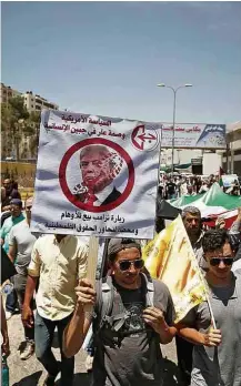  ?? Mohamad Torokman/Reuters ?? » PALESTINA Manifestan­te segura cartaz anti-Trump em Ramallah, na Cisjordâni­a, um dia antes de o presidente se reunir com o dirigente palestino Mahmoud Abbas