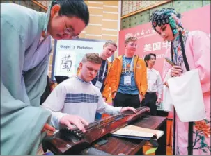  ?? YIN GANG / XINHUA guqin, a ?? Chinese students teach a high school student from the US state of Washington how to play classical Chinese instrument, at Peking University, in Beijing on March 20.