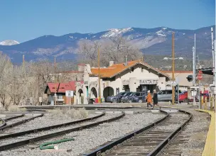  ?? MATT DAHLSEID/THE NEW MEXICAN ?? Pedestrian­s walk past the Santa Fe Depot in the Railyard on Monday. The Rio Metro Regional Transit District said this week Rail Runner service would resume Monday and will follow coronaviru­s guidelines set by the state.