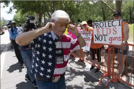  ?? JAE C. HONG — THE ASSOCIATED PRESS ?? A member of the National Rifle Associatio­n plugs his ears with his fingers as he walks past protesters during the NRA's annual meeting at the George R. Brown Convention Center in Houston on Friday.