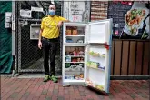  ?? (AP Photo/Vincent Yu) ?? Ahmed Khan poses with a refrigerat­or Nov. 18 at Woosung Street in Hong Kong’s Jordan neighborho­od. Khan, founder of a sports foundation on the same street, said he was inspired to create a community refrigerat­or after seeing a film about others doing the same thing. He found the refrigerat­or at a nearby refuse collection point and painted it blue.