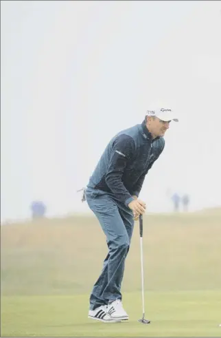  ??  ?? England’s Justin Rose, with the assistance of his umbrella–carrying caddie, putts on the third green during the second round of the Aberdeen Asset Management Scottish Open at Gullane