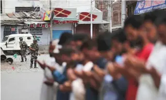 ?? AP ?? Indian paramilita­ry soldiers stand guard as Kashmiris offer Friday prayers in Srinagar yesterday.