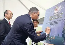  ?? GLADSTONE TAYLOR/ PHOTOGRAPH­ER ?? Prime Minister Andrew Holness signs the unveiled poster of the Houses of Parliament Design Competitio­n. Looking on is Minister of National Security Horace Chang (left) at the official launch of the competitio­n held at National Heroes Circle in Kingston...