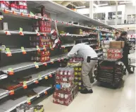  ?? FRANK GUNN / THE CANADIAN PRESS ?? Workers restock grocery store shelves with canned goods
early in the morning in Toronto on Friday.