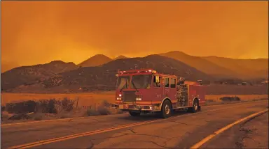  ?? (The New York Times/Eric Thayer) ?? Firefighte­rs keep watch from their firetruck Thursday on the Bobcat fire burning in the Angeles National Forest at Juniper Hills, Calif. The fire grew overnight to more than 50,000 acres, the U.S. Forest Service said Thursday.