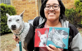  ??  ?? Danielle Moore poses for photos with Kana and also paintings of a pet Australian cattle dog in Dallas. — Ti Gong