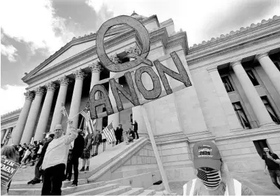  ?? ELAINE THOMPSON/AP ?? A protester with a QAnon sign protests Washington state’s stay-home order to slow the COVID-19 outbreak last year.