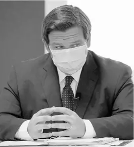  ?? LYNNE SLADKY/AP ?? Gov. Ron DeSantis listens during a news conference at the old Pan American Hospital during the coronaviru­s pandemic July 7 in Miami.