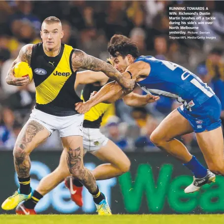  ?? Picture: Darrian Traynor/AFL Media/Getty Images ?? RUNNING TOWARDS A WIN: Richmond’s Dustin Martin brushes off a tackle during his side’s win over North Melbourne yesterday.