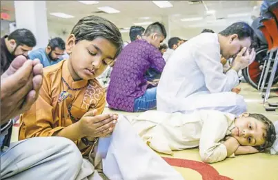  ?? Andrew Rush/Post-Gazette ?? Zirgham Khilji, 7, left, of South Fayette prays as Hamza Muhammad, 5, of Monroevill­e, rests while celebratin­g Eid al-Fitr on Friday. For a video, visit post-gazette.com.