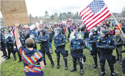  ??  ?? State troopers in riot gear form a line separating pro-Trump and anti-Trump demonstrat­ors gathered at the state capitol in Olympia, Washington, on Saturday. Washington state police reported the arrests of three demonstrat­ors.