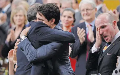  ?? CP PHOTO ?? Prime Minister Justin Trudeau hugs Liberal MP Rob Oliphant as Liberal MP Randy Boissonnau­lt (right) wipes a tear after making a formal apology to individual­s harmed by federal legislatio­n, policies, and practices that led to the oppression of and...