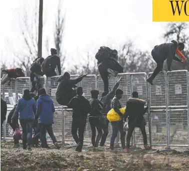  ?? OZAN KOSE / AFP VIA GETTY IMAGES ?? Migrants jump over fences erected by the Turkish army near the Pazarkule border gate in Edirne on Wednesday, during their journey to try to enter Europe. One migrant was killed by what Turkish officials claimed was Greek fire.