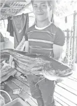  ??  ?? FARIDZUAN bersama ikan tapah seberat 6.8 kilogram yang ditangkapn­ya.