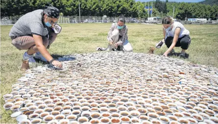  ?? REUTERS ?? Artist Aida Sehovic (centre) helps install her collection of some 8,000 traditiona­l ceramic cups filled with Bosnian coffee at the Potocari-srebrenica Memorial Centre for victims of the 1995 massacre of Muslim men and boys by Serb forces, in eastern Bosnia.