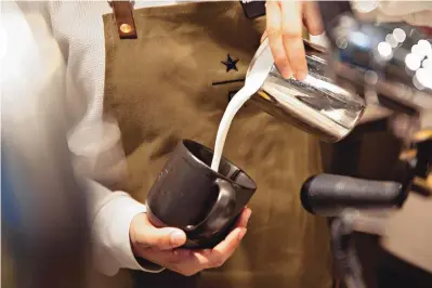  ?? DANIEL ACKER/BLOOMBERG ?? A barista pours milk into a cup while preparing a cappuccino at a Starbucks Reserve Roastery in Chicago in November 2019.