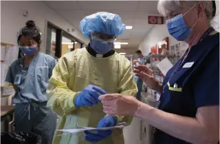  ?? JONATHAN HAYWARD THE CANADIAN PRESS ?? Rev. Victor Fernandes puts on protective gear prior to visiting with a patient in the COVID-19 intensive care unit at St. Paul’s hospital in Vancouver on Tuesday.