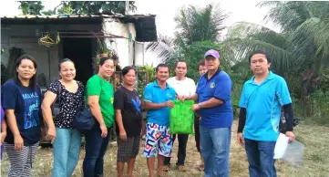  ??  ?? Andrew (second right) distribute­s love gifts to residents of Tudan resettleme­nt housing scheme.