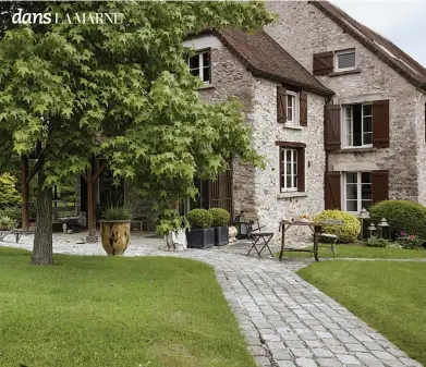  ??  ?? AU BOUT DE L’ALLÉE, la maison se révèle, bien campée dans son écrin végétal. Un vase d’Anduze ajoute un brin de couleur à la verdure.