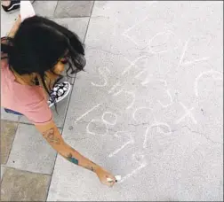  ??  ?? MISA RASHID, a sophomore at Azusa Pacific, writes her sentiments in chalk after the rally by the LGBTQ Christian community on campus.