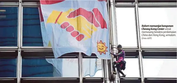  ?? (Foto AFP) ?? Robert memanjat bangunan Cheung Kong Center untuk memasang bendera perdamaian China dan Hong Kong, semalam.