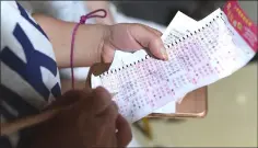  ??  ?? Checking a lottery ticket at a China Sports Lottery outlet.