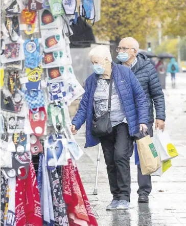  ?? PHOTO AFP ?? Un couple s’arrête à un kiosque de masques et de souvenirs, à Dublin, en Irlande.