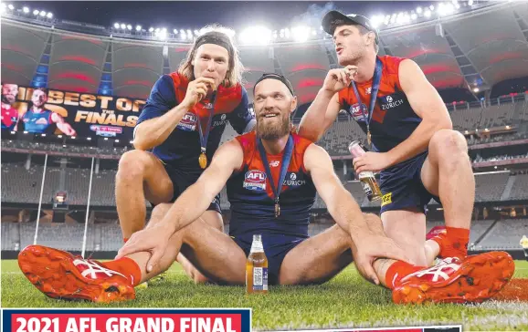  ?? ?? ABOVE: Demons Ed Langdon, Max Gawn and Angus
Brayshaw celebrate.
LEFT: Gawn with coach Simon Goodwin holding aloft the premiershi­p cup.
Pictures: Michael Willson/afl Photos via Getty Images