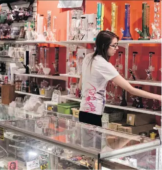  ?? CHRIS YOUNG/THE CANADIAN PRESS ?? An employee reaches for a bong at the Hotbox Cafe in Toronto. Research suggests a premium in prices for homes near retail pot stores and those sold in areas that legalized the drug.