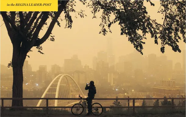  ?? JASON FRANSON/THE CANADIAN PRESS ?? A morning commuter stops to take a photograph of Edmonton as smoke from hundreds of B.C. wildfires cast an orange tinge over the city on Wednesday.