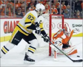  ?? TOM MIHALEK — THE ASSOCIATED PRESS ?? Pittsburgh’s Sidney Crosby, left, shoots as Flyers goalie defends during the first period in Game 4 Wednesday. Brian Elliott