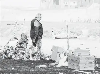  ?? JONATHAN HAYWARD THE CANADIAN PRESS ?? Myles Shumlanski pauses at a makeshift memorial at the intersecti­on where the Humboldt Broncos bus met disaster near Tisdale, Sask.