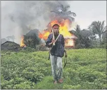  ??  ?? An ethnic Rakhine man holds homemade weapons as he walks in front of houses that were burnt during fighting in Sittwe, Myanmar.