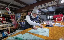  ?? ROBERT F. BUKATY — THE ASSOCIATED PRESS ?? Karen Haley cuts cotton fabric for masks to be given to caregivers during the coronaviru­s outbreak, at the North Sails shop in Freeport, Maine.