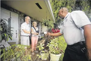  ?? BRUCE R. BENNETT / THE PALM BEACH POST ?? Boynton Beach community standards outreach coordinato­r Courtney Cain gives his business card to Jim and Evelyn Trotter in the Golfview Harbour neighborho­od recently. After noticing a car without a license plate in the driveway, Cain knocked on the...