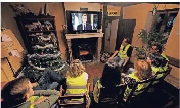  ?? FOTO: REUTERS ?? Franzosen mit gelben Westen sehen sich die Rede ihres Präsidente­n Emmanuel Macron im Fernsehen an.