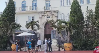  ??  ?? Visitors pose for photograph­s and read a restaurant menu in front of The Villa Casa Casuarina.