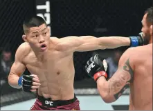  ?? ZUFFA LLC ?? Li Jingliang of China goes on the attack against Santiago Ponzinibbi­o of Argentina during their welterweig­ht bout at UFC Fight Island 7 at Etihad Arena in Abu Dhabi, United Arab Emirates, on Saturday night. Li won with a first-round knockout.