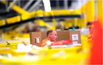  ?? – AFP photo ?? In this file photo, Amazon employees work at the Amazon Fulfillmen­t Center in Robbinsvil­le, New Jersey.