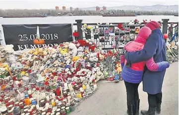  ?? — Reuters photo ?? People visit a makeshift memorial on the day of national mourning for the victims of a shopping mall fire in Kemerovo on an embankment of the Yenisei River in the Siberian city of Krasnoyars­k, Russia.