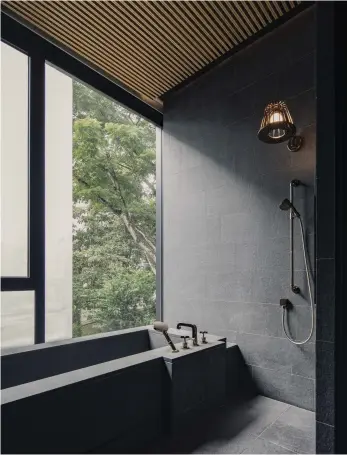  ??  ?? This page
Inspired by Japanese onsens, the master bathroom features a granitecla­d built-in bathtub and gold accents, while the timber ceiling overhead echoes the entrance pavilion