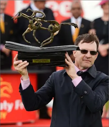  ??  ?? Trainer Aidan O’Brien lifts the trophy after winning the Dubai Duty Free Irish Derby with Capri on Saturday.