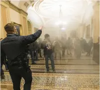  ?? MANUEL BALCE CENETA/AP ?? Smoke fills the walkway outside the Senate Chamber as supporters of former President Donald Trump are confronted by U.S. Capitol Police officers inside the Capitol on Jan. 6, 2021.