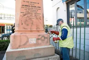  ??  ?? a worker painting over graffiti on the base of a statue of James Cook in a Sydney suburb that had been vandalised by australian­s objecting to problemati­c historical figures. — Reuters/aaP